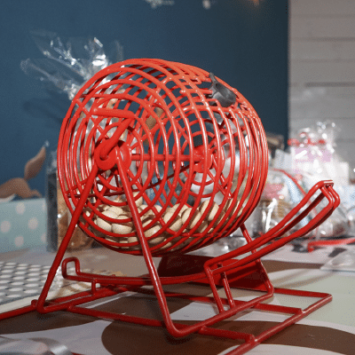 Feb 25, Plant Bingo: Red wire bingo cage filled with bingo balls on a table.